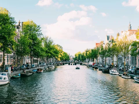 Canal de Ámsterdam rodeado de árboles y edificios típicos.