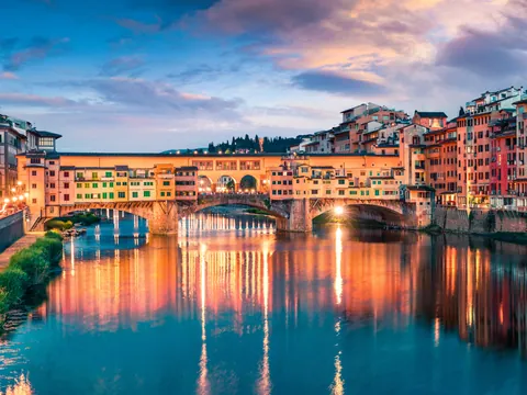 Ponte Vecchio iluminado al anochecer sobre el río Arno en Florencia