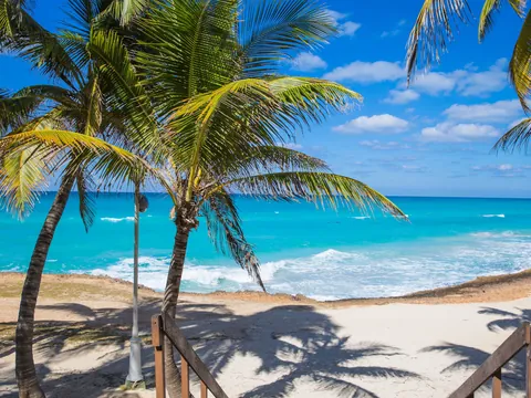 Un escenario idílico donde el mar, la arena y el cielo se encuentran en perfecta armonía, creando un espacio para la relajación y el disfrute.