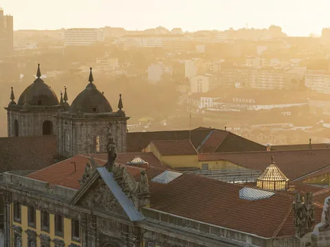 Vista de Oporto al atardecer con tejados históricos y la ciudad iluminada por luz dorada.