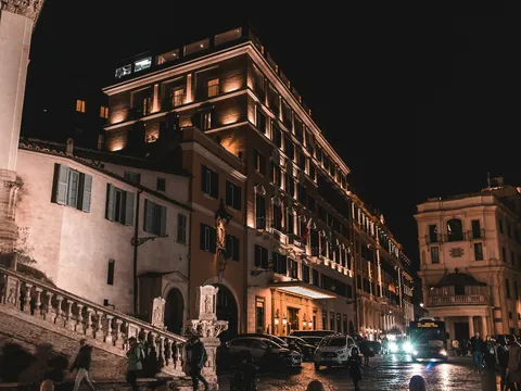 Calle iluminada de Roma de noche con edificios históricos y gente paseando