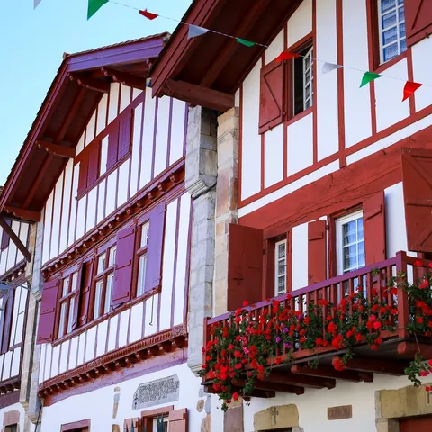 Casas tradicionales con entramado rojo y flores en balcones en Ainhoa, pueblo del País Vasco francés.
