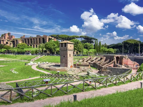 Ruinas de las Termas de Caracalla en Roma, con altos muros de ladrillo, arcos monumentales y áreas verdes bajo cielo despejado.