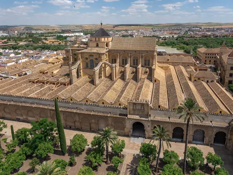 Vista aérea Mezquita de Córdoba, tejados, cúpula dorada, palmeras y ciudad al fondo