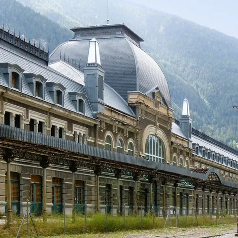 Fachada principal de la Estación Internacional de Canfranc con una gran cúpula y el Pirineo al fondo.