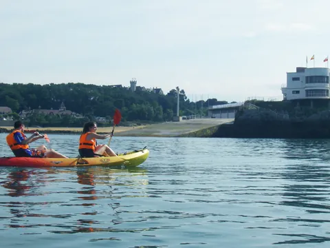 Pareja en kayak doble navegando frente a la Isla de la Torre en la bahía de Santander