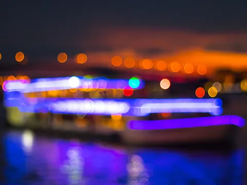 Barco iluminado con luces de colores navegando de noche.