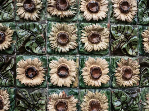 Azulejos cerámicos con girasoles en relieve y fondo verde.