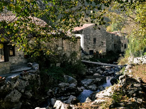 Pueblo de Bulnes, Asturias, con casas de piedra, un arroyo y un pequeño puente de madera en Picos de Europa.