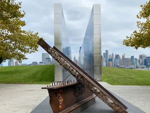 Monumento conmemorativo del 11S con vigas de acero y vista de Manhattan desde Liberty State Park.