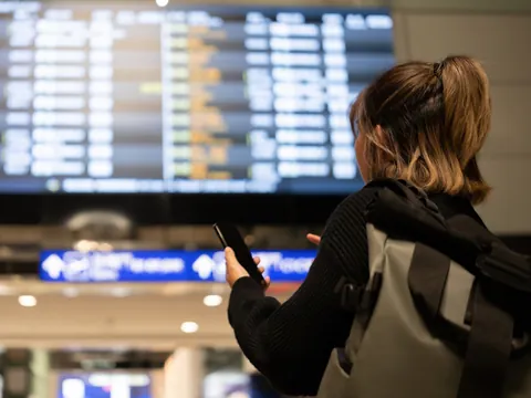 Chica mira una lista de vuelos en el aeropuerto. Si el vuelo sufre algún retraso el chófer lo sabrá.