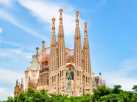 Vista frontal de la Sagrada Familia en Barcelona rodeada de vegetación