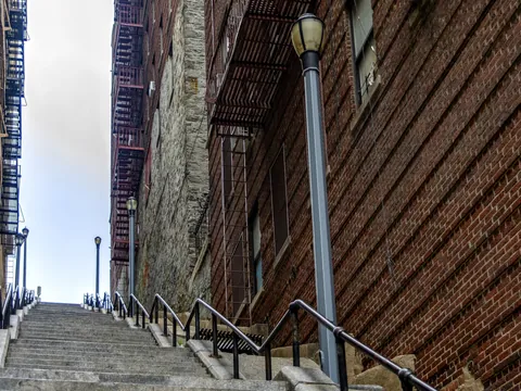 Las icónicas escaleras de 'Joker' en El Bronx, Nueva York, flanqueadas por edificios de ladrillo y farolas.