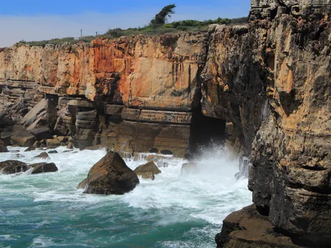 Acantilados de Cascais con olas rompiendo en la cueva de la Boca do Inferno.