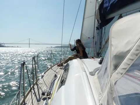 Persona disfrutando de un paseo en velero por el Tajo con el puente al fondo.