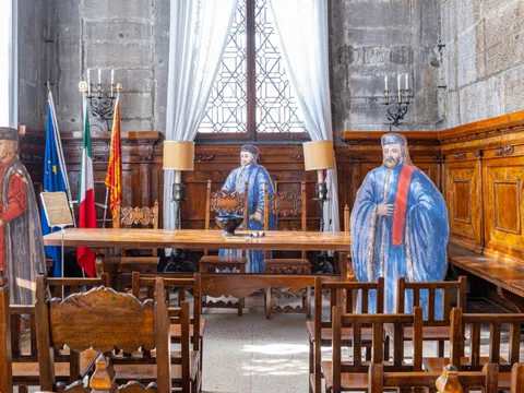 Caballeros de la Noche observando desde la sombra en una sala de juicio, presentes como figuras de autoridad en un tribunal medieval.