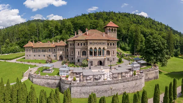 Panorámica del Castillo de Cantacuzino y su entorno, con vegetación y montañas alrededor del edificio.