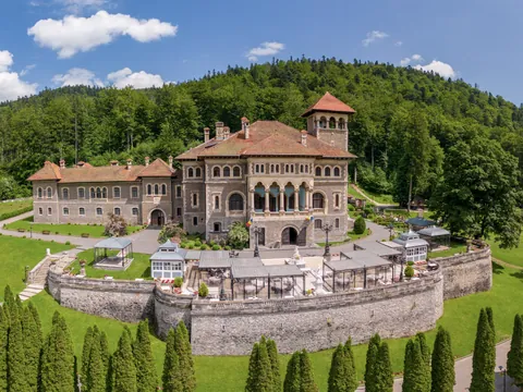 Panorámica del Castillo de Cantacuzino y su entorno, con vegetación y montañas alrededor del edificio.
