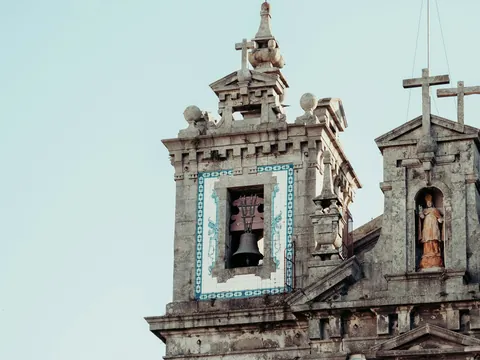 Campanario y fachada de una iglesia histórica en Oporto con detalles de piedra y azulejos.
