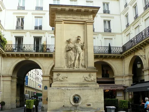 Fuente de Jussieu en una plaza rodeada de edificios clásicos y terrazas en París