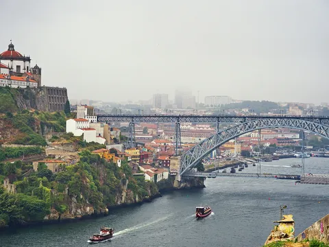 Vista del puente de Don Luis I con barcos navegando por el Duero en día de niebla.
