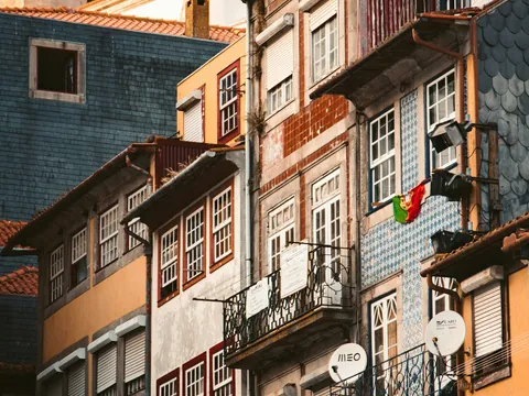 Fachadas coloridas y tradicionales de Oporto con balcones, azulejos y una bandera portuguesa.
