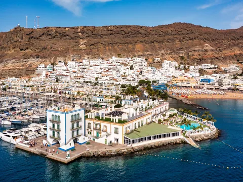 Vista aérea de Puerto de Mogán, donde se ve la playa, la localidad al completo y las montañas de los alrededores.
