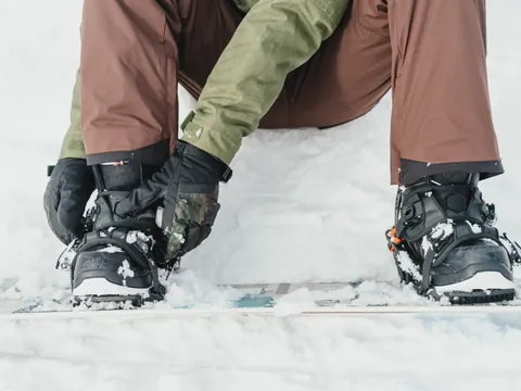 Botas de snowboard de alquiler ajustándose en Fuentes de Invierno, Asturias