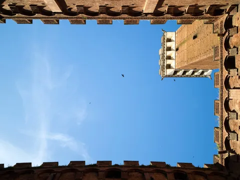 Vista desde patio medieval con torre y cielo azul en la Toscana, Italia
