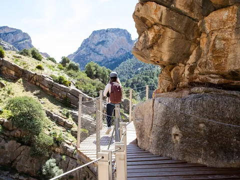 Mujer con casco y mochila caminando por la pasarela del Caminito del Rey