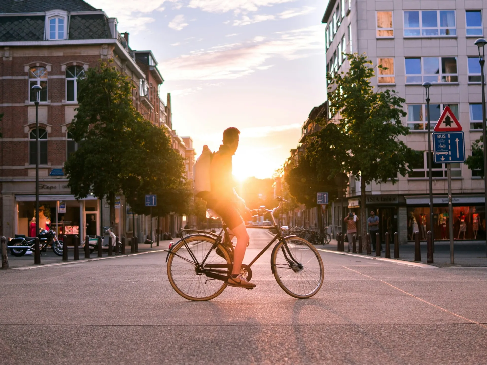 Ciclista cruzando una calle de Bruselas durante el atardecer.