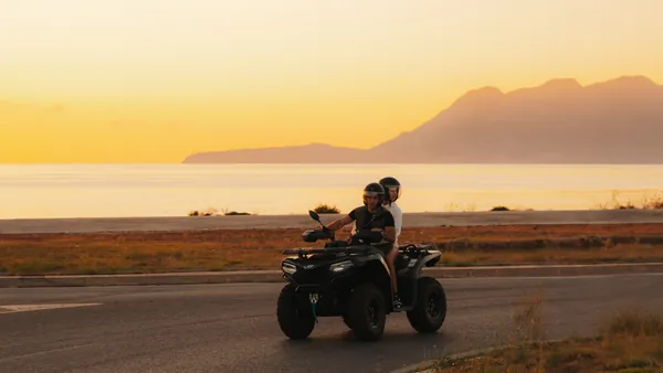 Dos personas recorren la costa mallorquina en un quad al atardecer