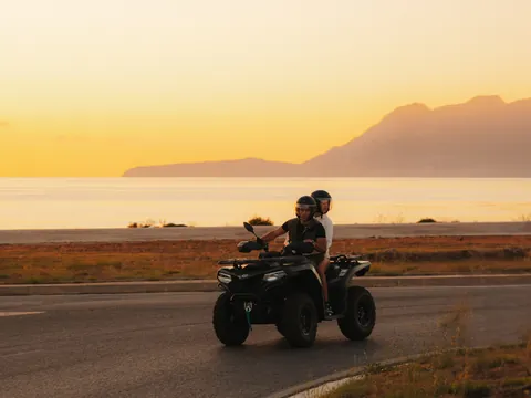 Dos personas recorren la costa mallorquina en un quad al atardecer
