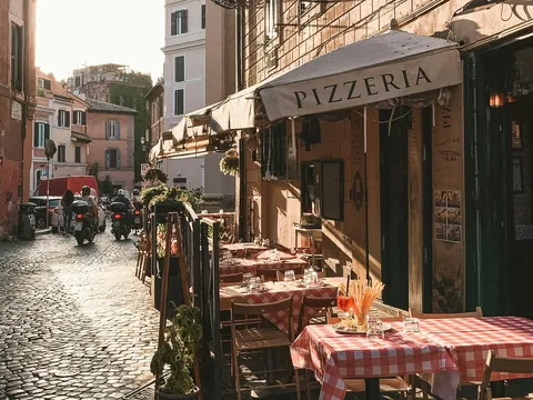 Terraza de pizzería en calle empedrada del barrio de Trastevere, Roma
