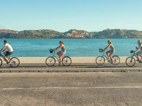 Grupo en bicicleta junto al río Tajo con vistas al Puente 25 de Abril en Lisboa