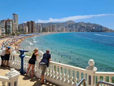 Personas observando la playa de Levante desde el mirador del paseo en Benidorm