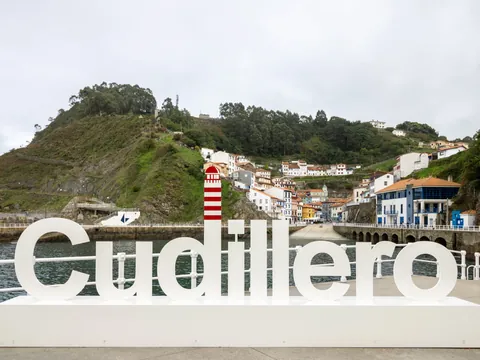 Letrero de Cudillero en el puerto con el pueblo al fondo, Asturias