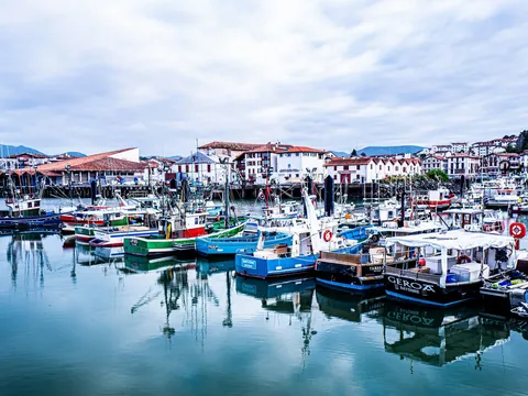 Puerto de San Juan de Luz con barcos de pesca y casas tradicionales junto al agua.