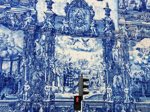 Mural de azulejos azules en Oporto con escenas religiosas y un semáforo en primer plano.