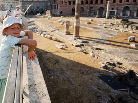 Niño observando las ruinas del Foro Romano desde una barandilla en Roma