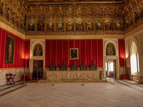 Sala del Trono en el Alcázar de Segovia con friso de reyes y tapices rojos.