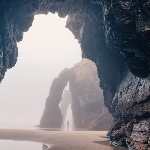 Arcos de piedra y acantilados de la Playa de las Catedrales, Ribadeo, Galicia, con ambiente brumoso.