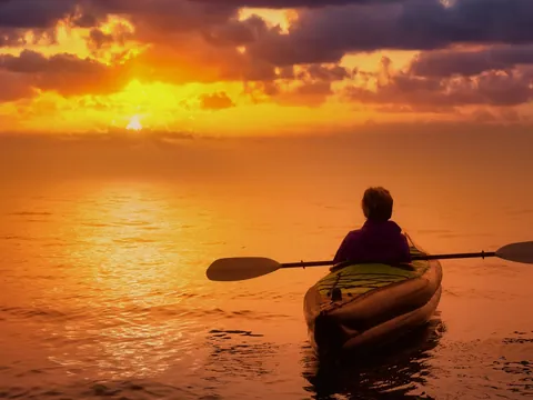 Persona en kayak contemplando un atardecer en Es Grau, Menorca