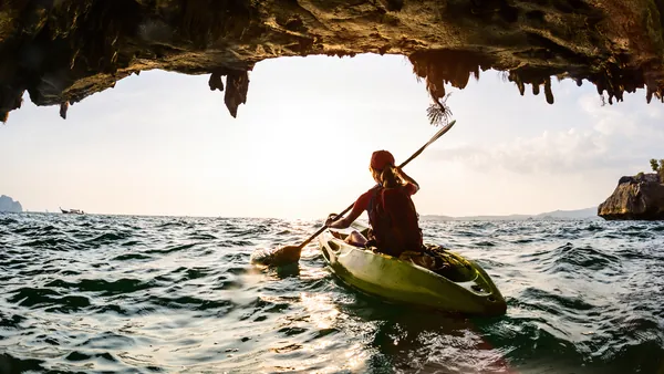 Persona en kayak saliendo de una cueva marina en Es Canutells