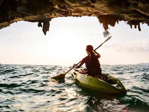 Persona en kayak saliendo de una cueva marina en Es Canutells