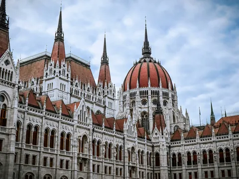 La fachada y cúpula del imponente Parlamento de Budapest bajo un cielo nublado.