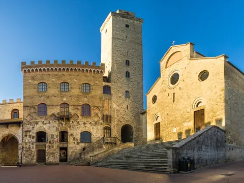 Plaza medieval en San Gimignano con torre de piedra y iglesia, Toscana, Italia.