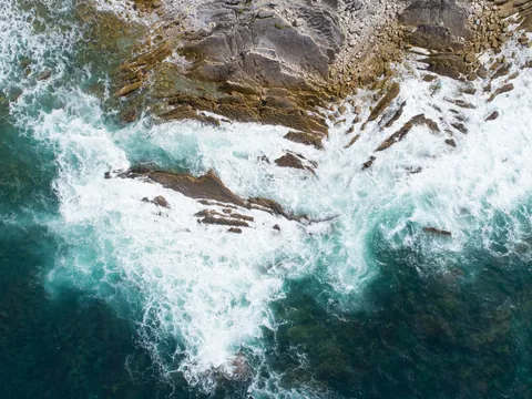 Olas rompiendo sobre rocas vistas desde arriba.
