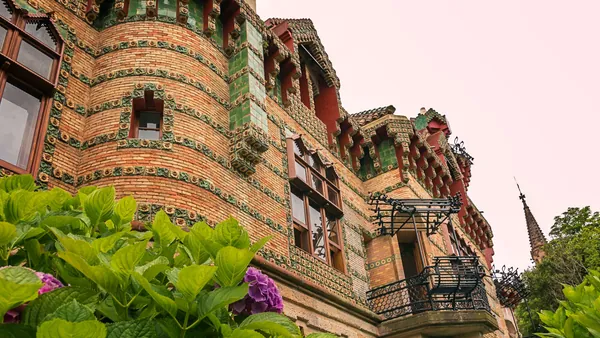 Fachada modernista de El Capricho de Gaudí en Comillas, Cantabria, con detalles cerámicos y flores.