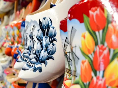 Zuecos de madera pintados a mano con diseños de tulipanes y molinos de viento, típicos de la artesanía holandesa, expuestos en una tienda.